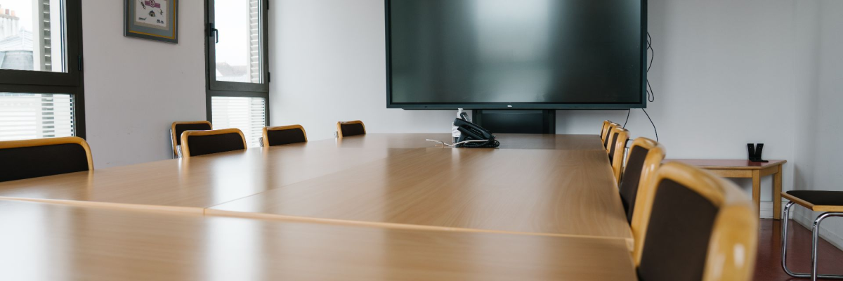 Salle avec table, chaises, écran, téléphone, cadre et fenêtre.