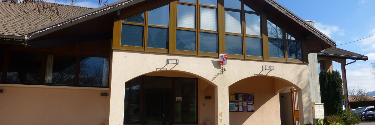 Bâtiment avec toiture en pente, grandes fenêtres et entrées doubles.