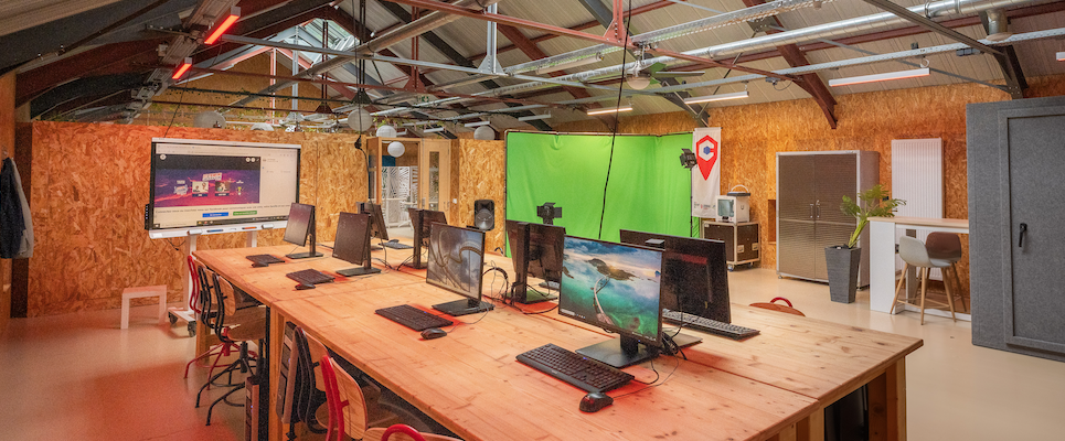 Bureau avec table, chaises, écrans, clavier et souris. Mur en bois et plafond industriel.