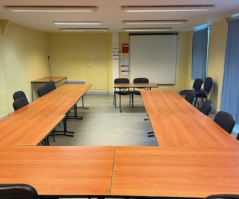 Salle de réunion avec tables, chaises et lumières.