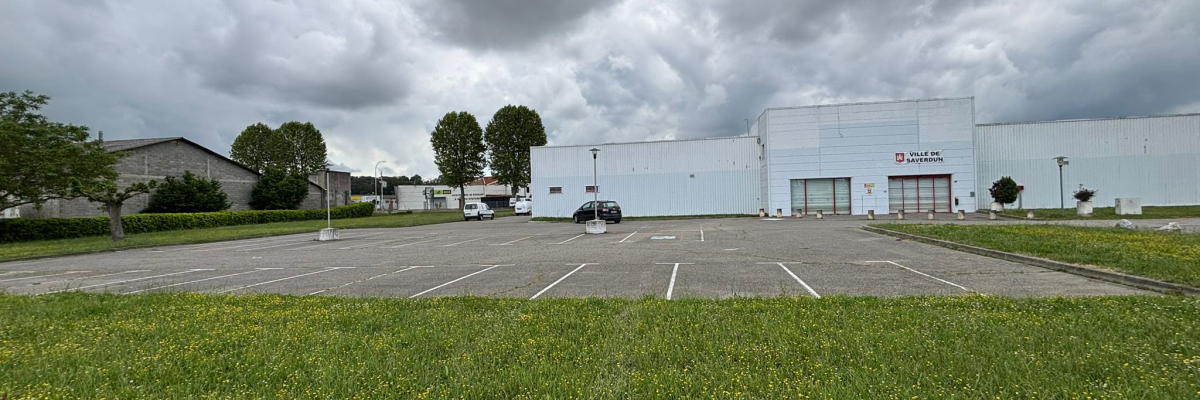 Bâtiment industriel avec parking vide et pelouse devant.
