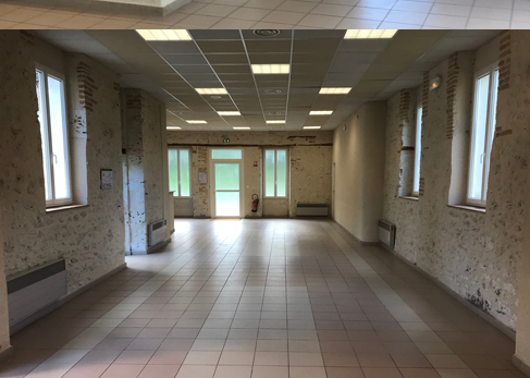 Courridor avec fenêtres, portes, radiateurs et éclairage au plafond.