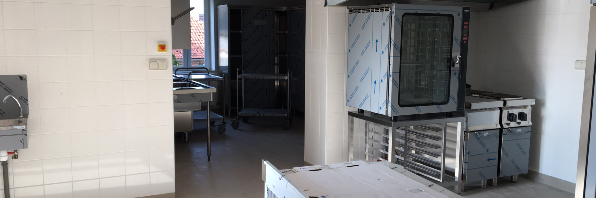 Cuisine avec fours, étagères, évier, plan de travail et boîte en carton.