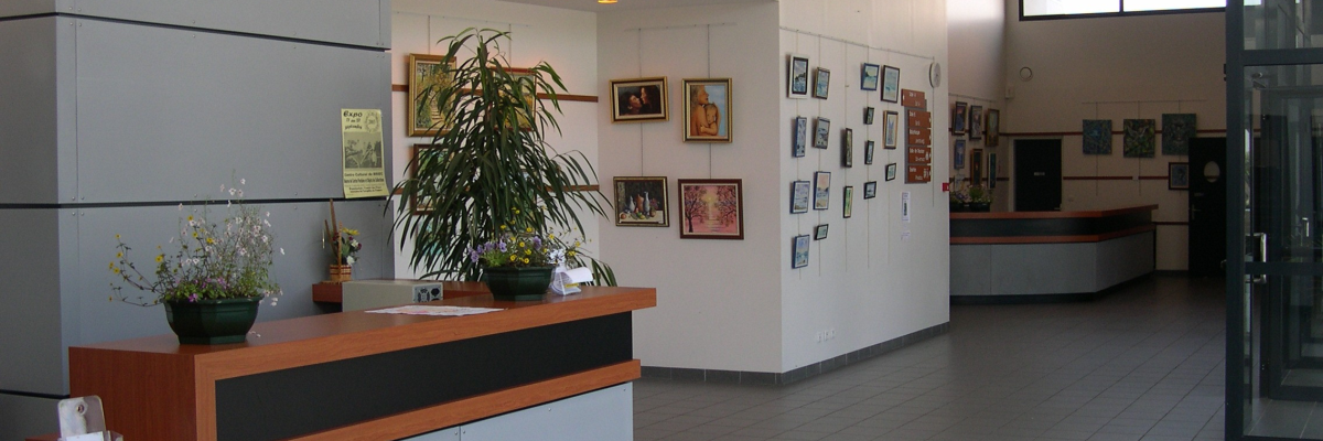 Réception avec comptoir, plantes, œuvres d'art au mur et porte vitrée.