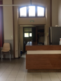Réception avec bureau, chaise, distributeur d'eau et porte vitrée.