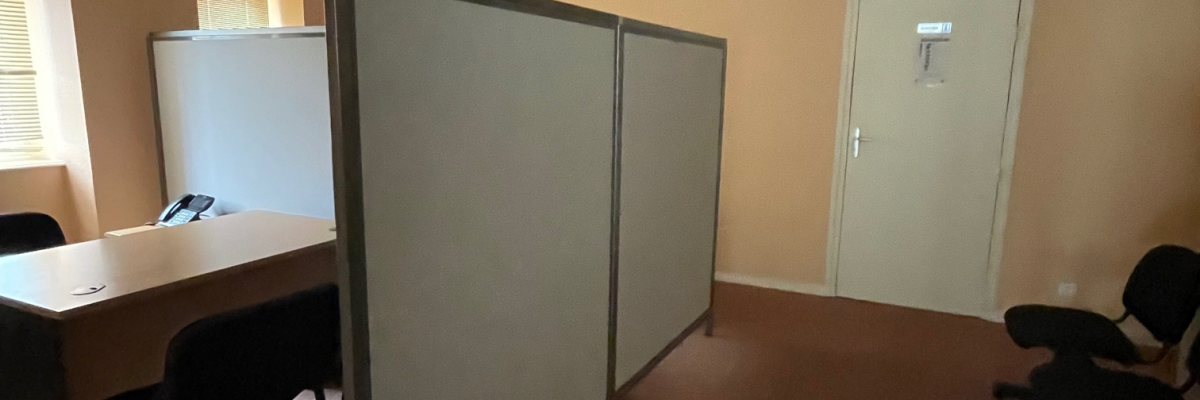 Bureau avec table, chaises, cloisons, et armoire.