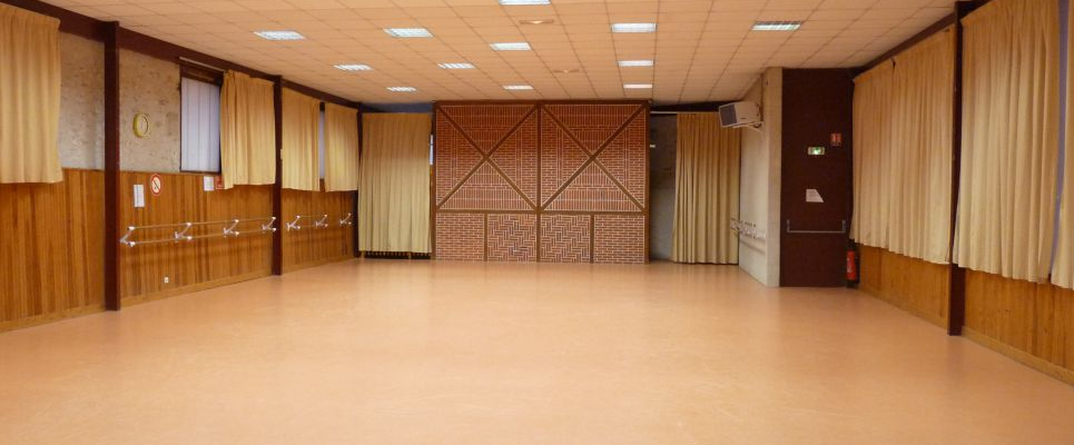 Salle vide avec éclairage au plafond, murs en bois, rideaux, porte et extincteur.