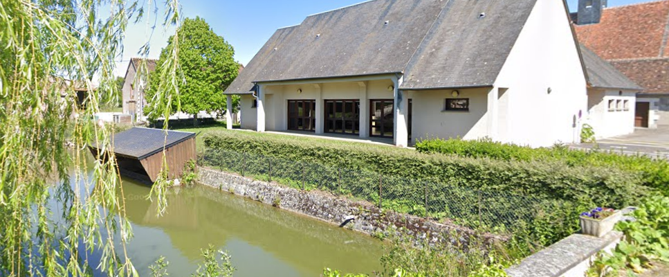 Maison près d'un étang, avec clocheton à l'arrière-plan.