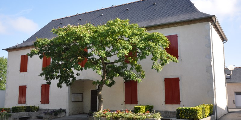 Maison avec volets rouges, arbre et buissons.