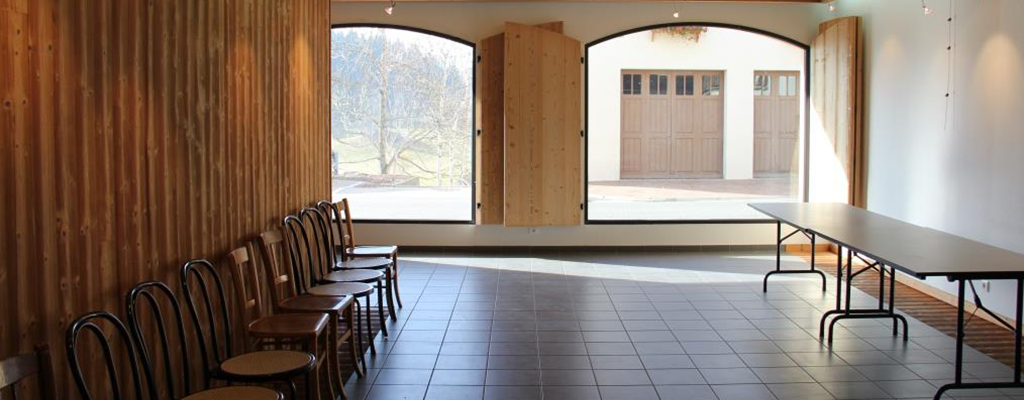 Salle avec tables, chaises, portes en bois et vue extérieure.