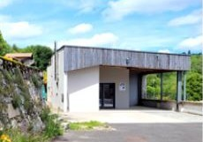 Bâtiment avec porte, toiture et parking.