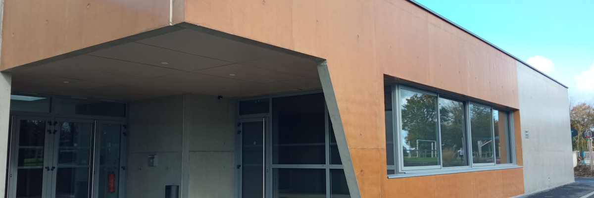 Bâtiment avec façade en bois, porte en verre et parking.
