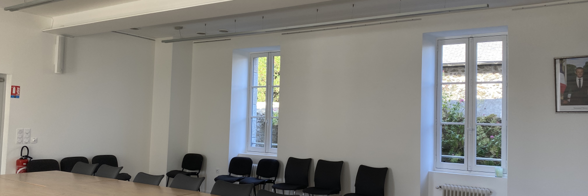 Salle de réunion avec table, chaises, vidéo projecteur, radiateur et tableaux.