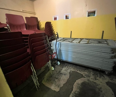 Pièces avec chaises empilées, tables pliantes et sol inondé.