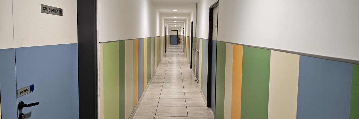 Couloir avec portes, murs colorés et éclairage au plafond.