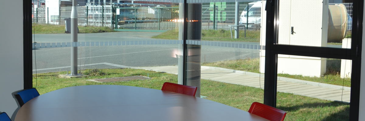 Salle ovale avec table, chaises et fenêtres vue sur l'extérieur.