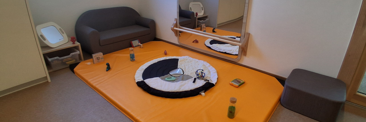 Chambre avec futon, table basse, canapé, miroir, tabouret, et divers objets sur la table.