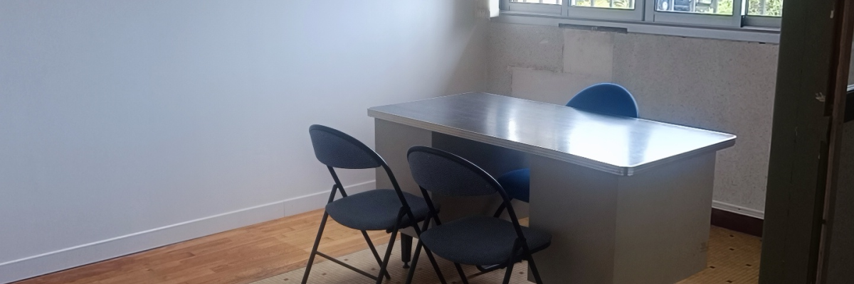 Chambre vide avec table, chaises, fenêtres et lumière.
