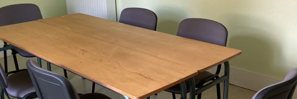 Salle avec table, chaises, radiateur et mur jaune.