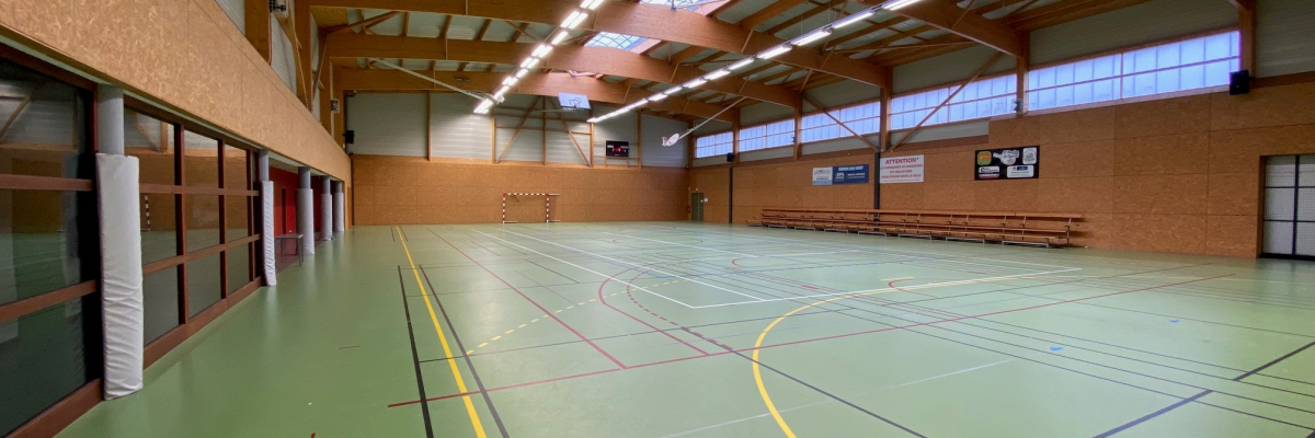 Salle de sport avec panneaux, terrain, gradins, paniers de basket.