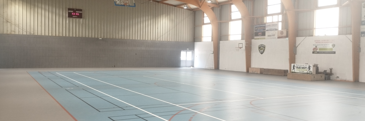 Salle de sport avec panier de basket, terrain de basket et bancs.