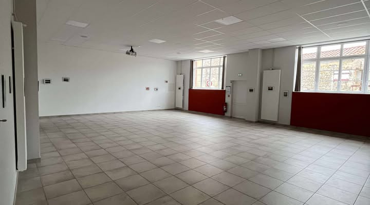 Salle vide avec carrelage, plafonds suspendus, lumières, portes et fenêtres.