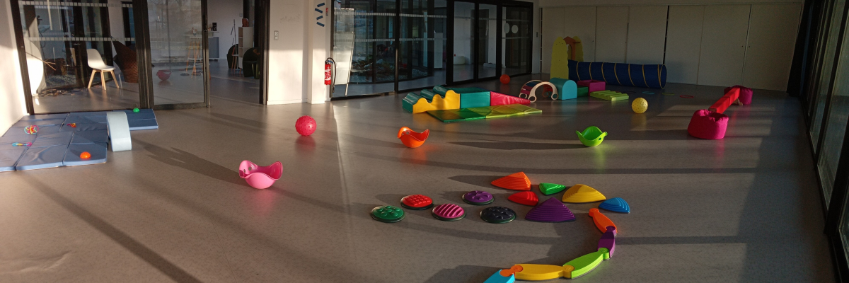 Salle avec jouets colorés, tapis de jeu, banco.