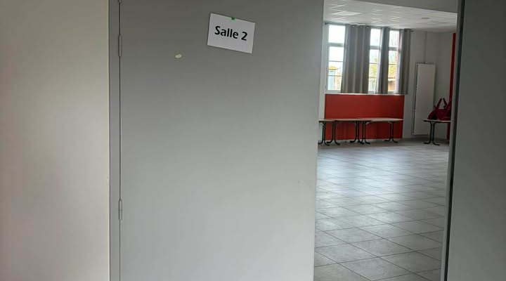 Porte ouverte menant à une salle avec tables et chaises.