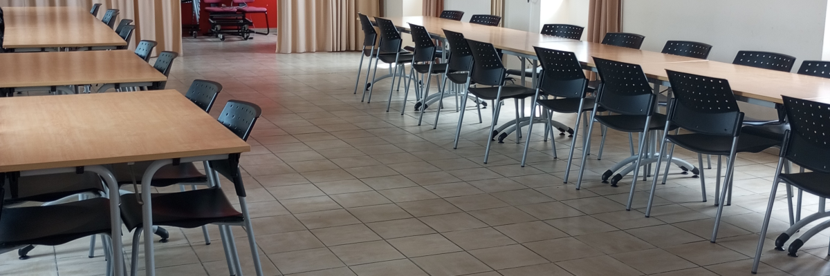 Salle avec tables, chaises, rideaux, horloge et luminaires.