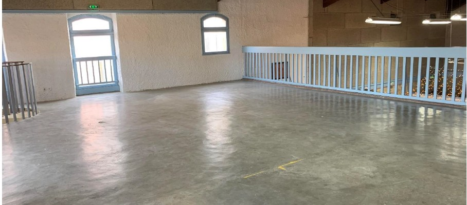 Atelier vide avec rampes, portes, fenêtres et éclairage au plafond.