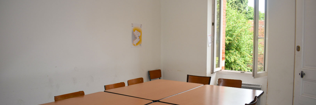 Salle avec tables, chaises, fenêtre, éclairage et tableau.