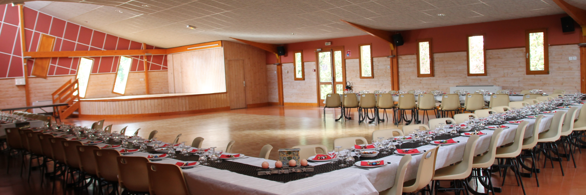 Salle avec tables, chaises, nappes, verres, couverts.