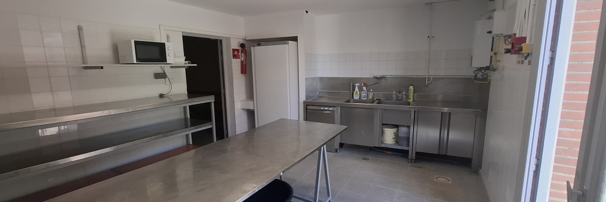 Cuisine avec plans de travail, évier, micro-ondes, placards et poubelle.