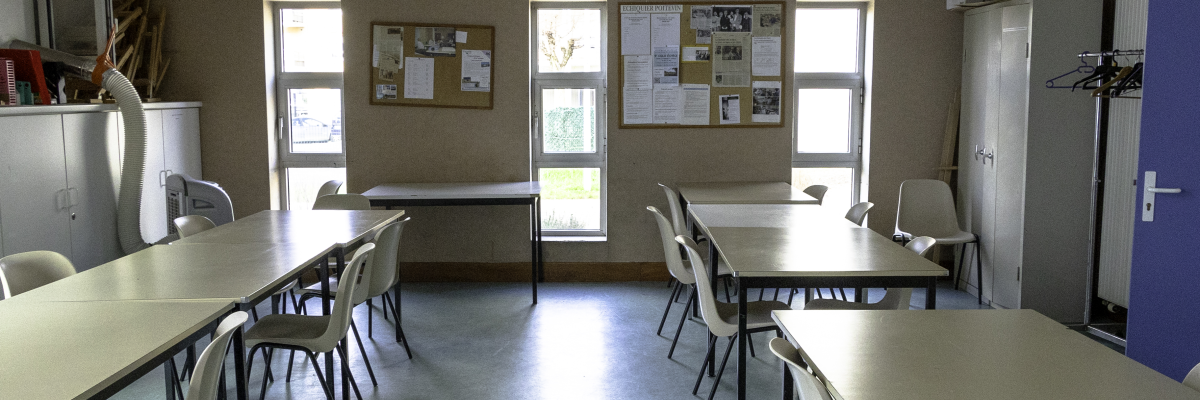 Salle avec tables, chaises, tableaux, armoires et horloge.