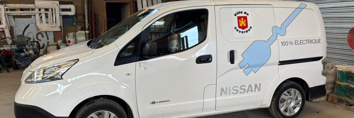 Utilitaire Nissan blanc dans un garage avec outils et étagères.