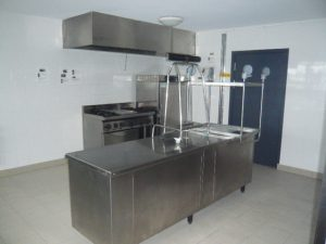 Cuisine avec plan de travail, étagères, plaques de cuisson, hottes et robinets.