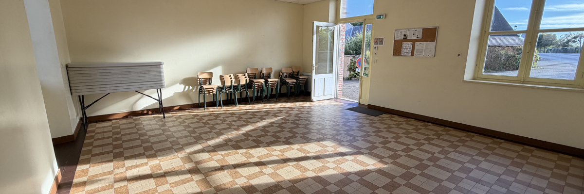 Salle avec chaises, table, fenêtres, porte et tableau d'affichage.