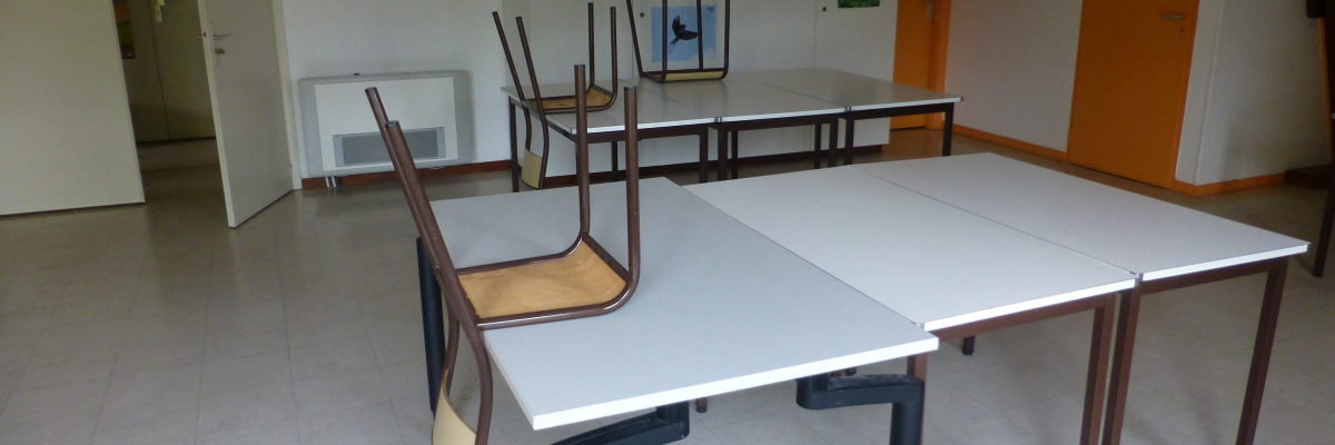 Salle avec tables, chaises, étagères et posters.