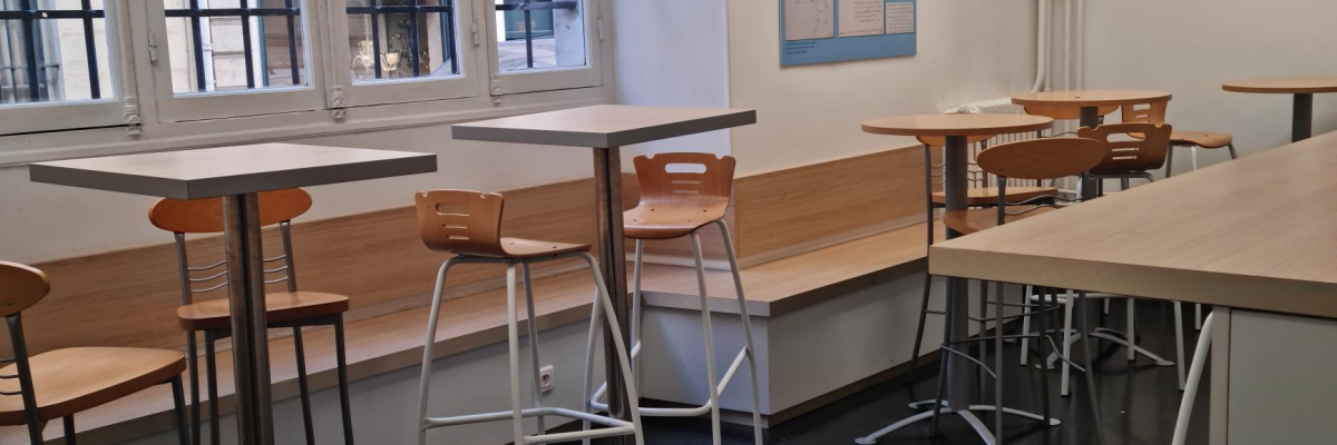 Salle avec tables, tabourets, chaises, vitres et luminaire rond au plafond.
