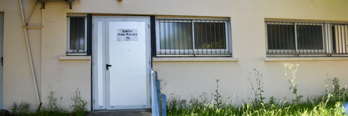 Bâtiment avec climatiseur, portes vitrées et herbe.