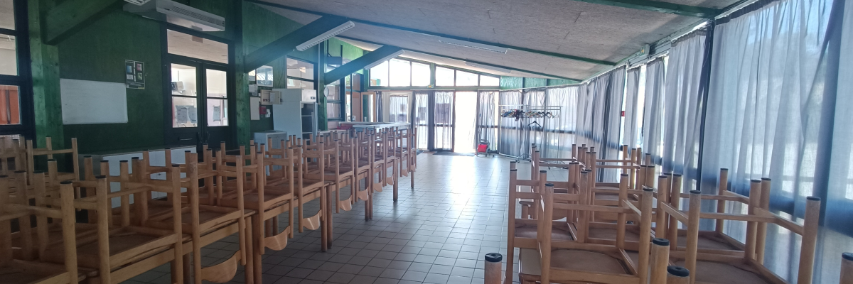 "Salle avec rangées de bancs, tables, portes vitrées et rideaux."