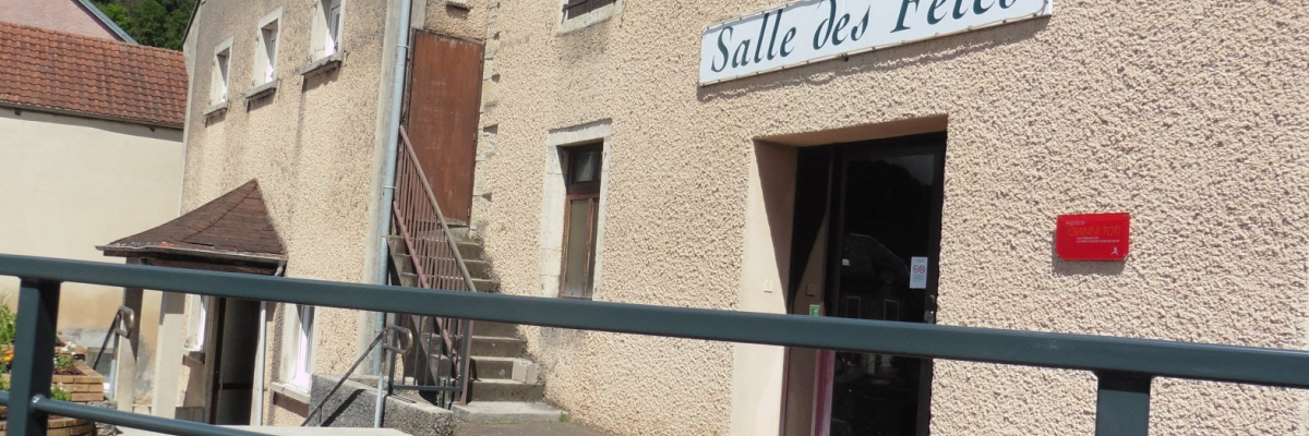 Bâtiment avec escalier extérieur, entrée principale et panneau "Salle des Fêtes".