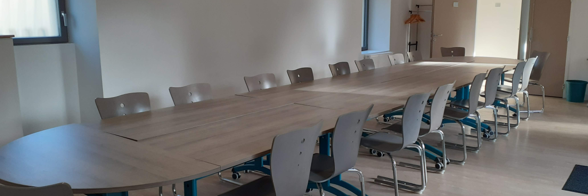 Salle de réunion avec table, chaises et porte-manteau.