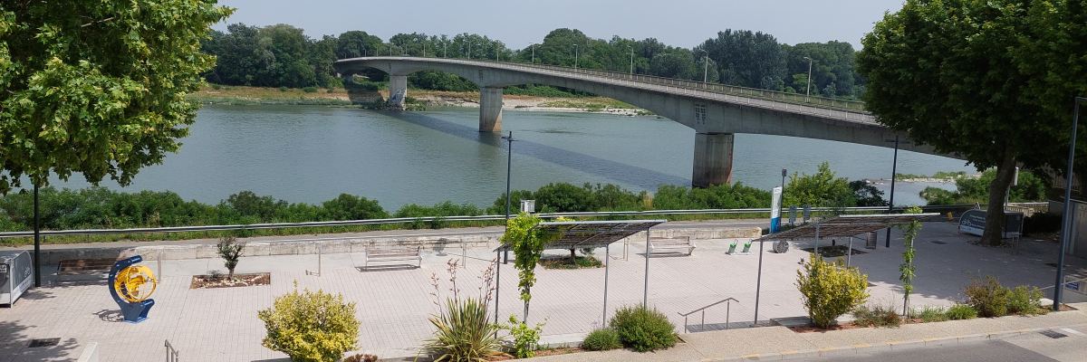 Vue de pont sur rivière, route et espace vert.