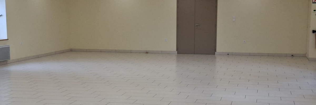 Salle vide avec porte et lumières au plafond. Sol carrelé. Mur beige.