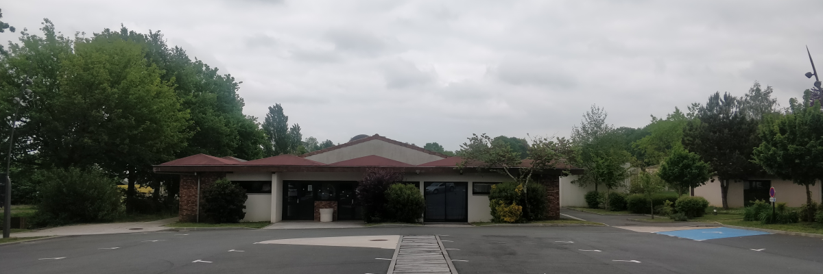 Parking avec allée en bois, bâtiments et arbres.