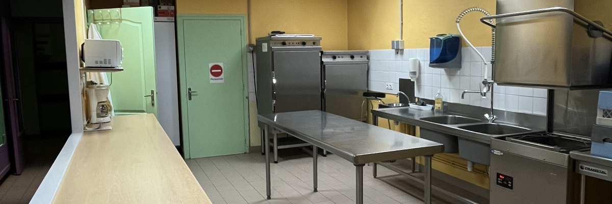 Cuisine avec plans de travail, évier, réfrigérateur, étagère et équipement de cuisine.