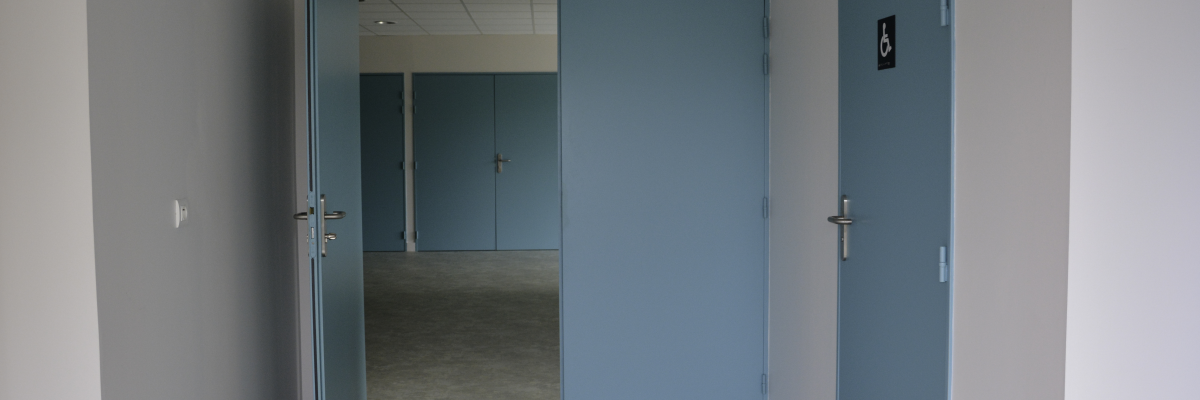 Couloir avec portes bleues, interrupteur et sol carrelé.