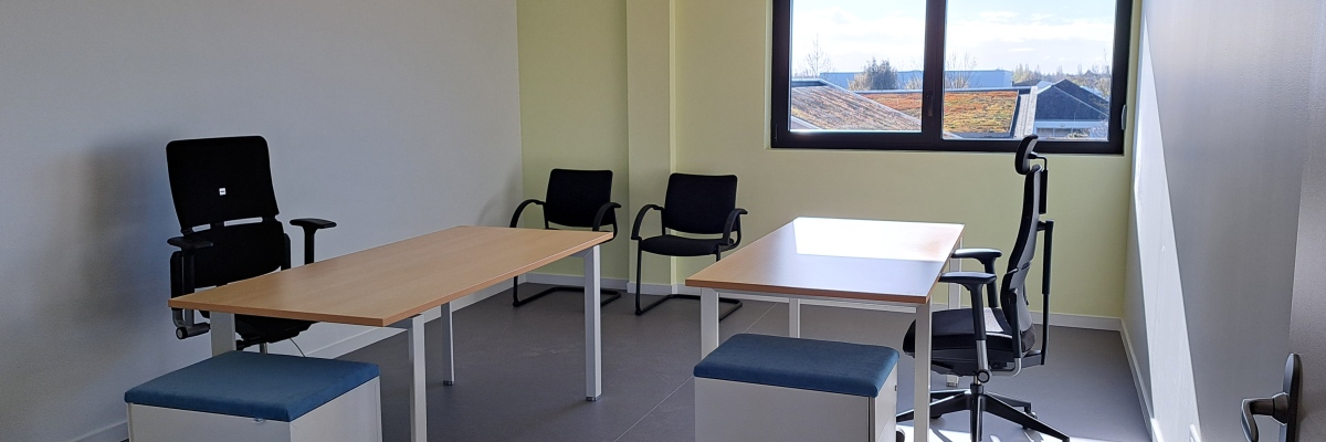 "Bureau équipé de tables, chaises, ottomans et fenêtre."