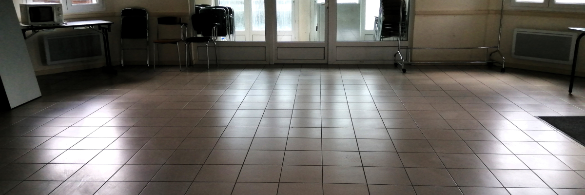 Salle vide avec chaises, porte-manteau, radiateur et fenêtre.